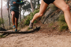 Two people running along a wooded trail