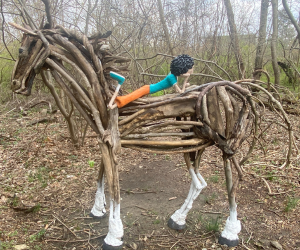 A horse made of sticks with a child reclined on its back