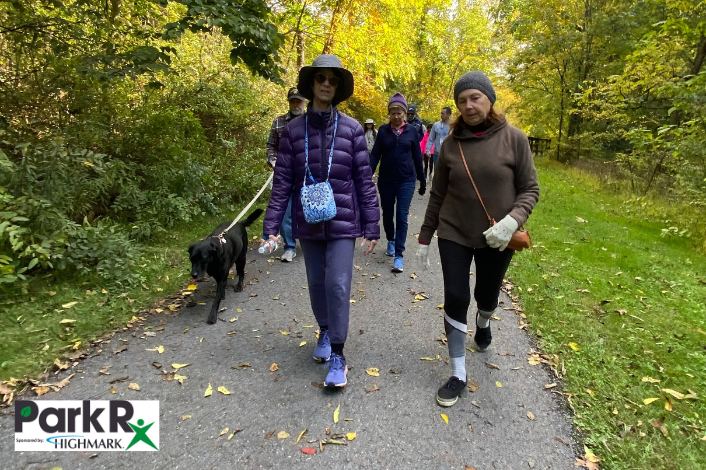 A group of people walking on a paved trail at Wildwood Park in jackets and hats