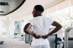 Man in a gym holding his lower back in pain