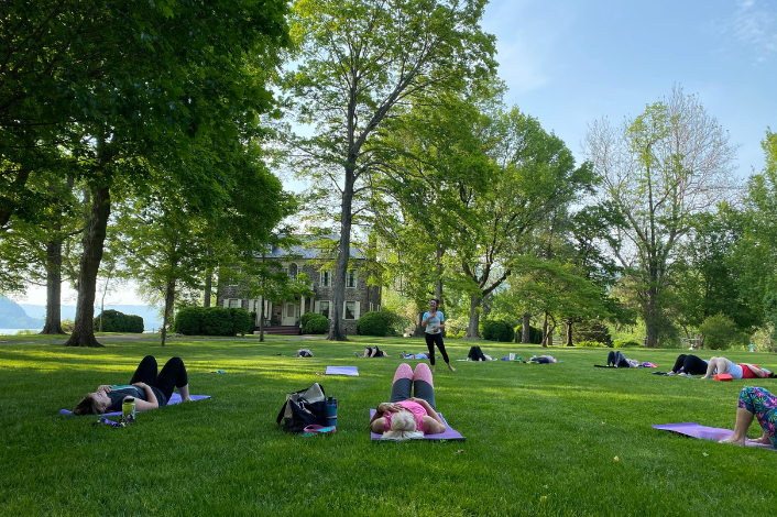 Group of people laying down on yoga mats in the green grass of Fort Hunter Park