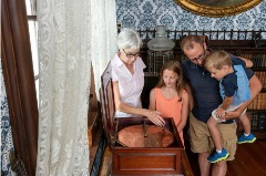 Adult tour guide showing a family an exhibit at the mansion.